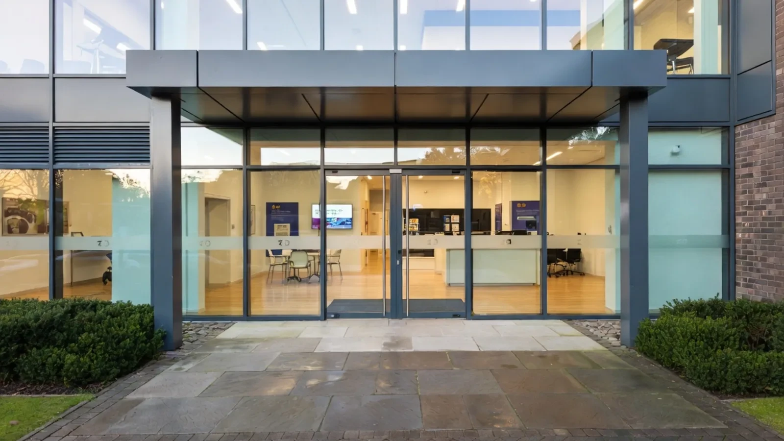 Modern office entrance with glass canopy and reception desk visible