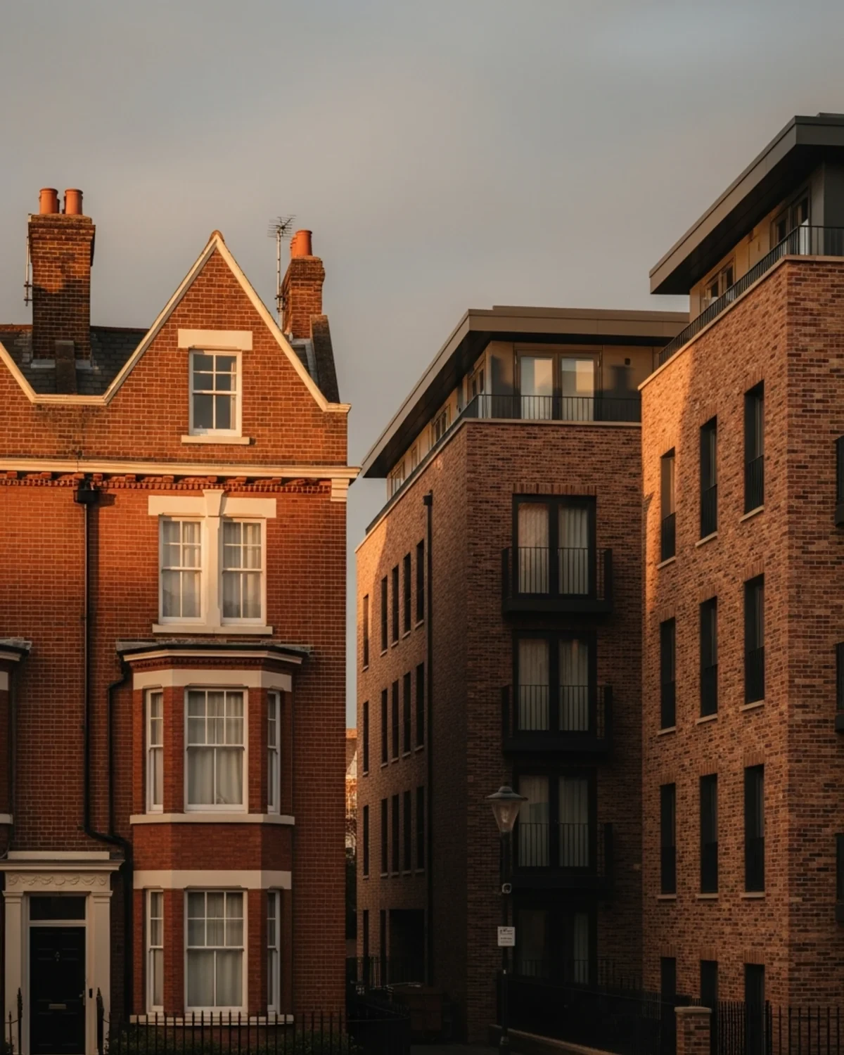 Red-brick period townhouses beside a contemporary residential building under warm evening light in the East Midlands